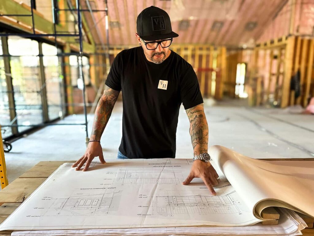 Versa Homes builder reviewing architectural drawings at a framed custom home site