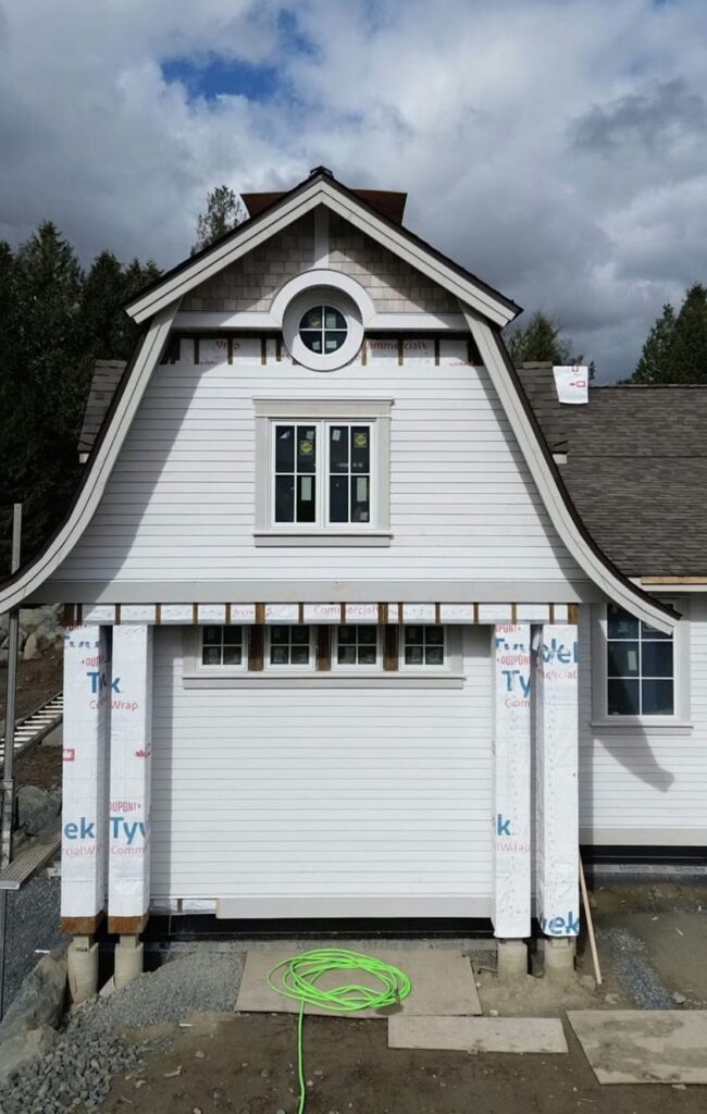 Coastal BC custom home showing partially installed siding over a rainscreen system with house wrap and furring strips visible
