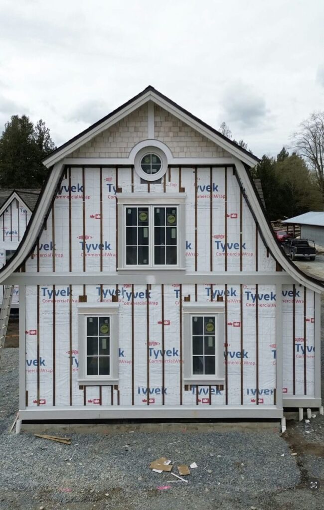 Exterior wall prepared for rainscreen cladding with vertical furring strips installed over Tyvek house wrap on a coastal BC custom home